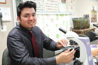 Male student placing specimen under microscope