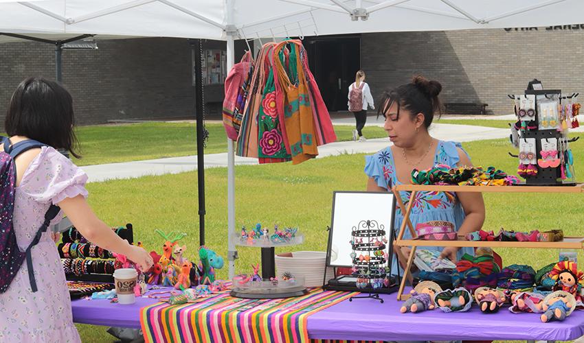 Vendor booth with colorful bags & dolls. 
