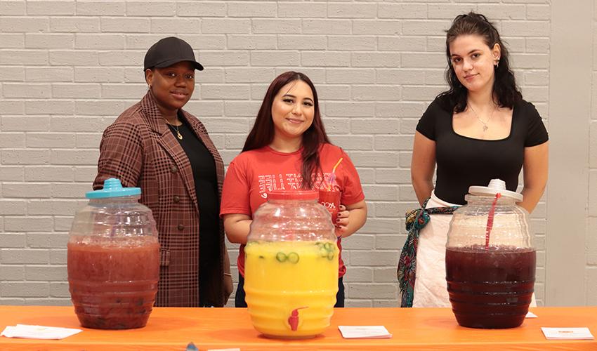 Three individuals providing refreshments at event name.
